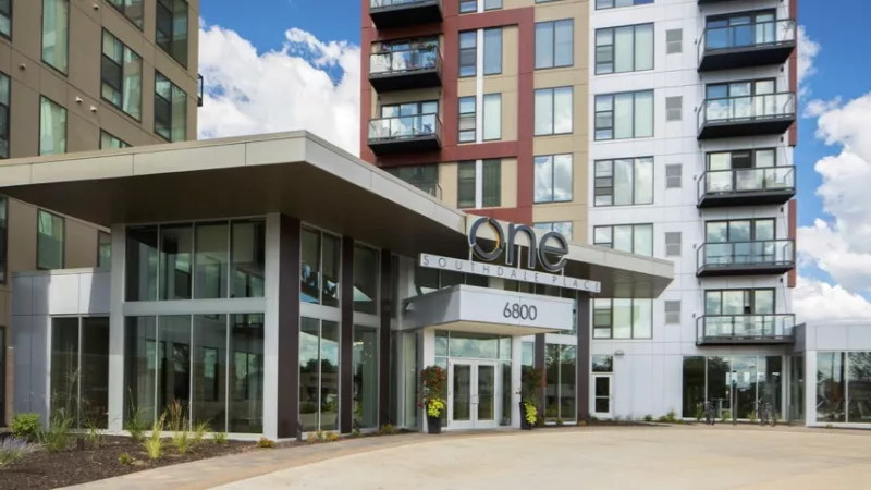 Modern high-rise building with a covered entrance marked "ONE 4800", featuring balconies and a colorful facade.